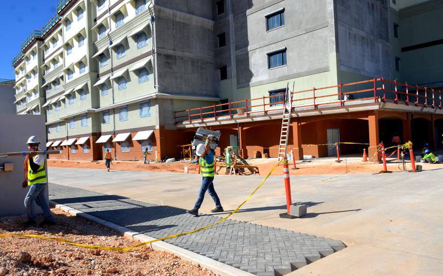 A person wearing a hard hat carries building supplies.