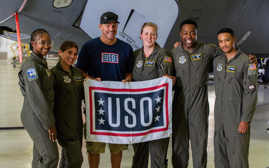 David Boreanaz poses with Air Force service members while holding a USO flag.