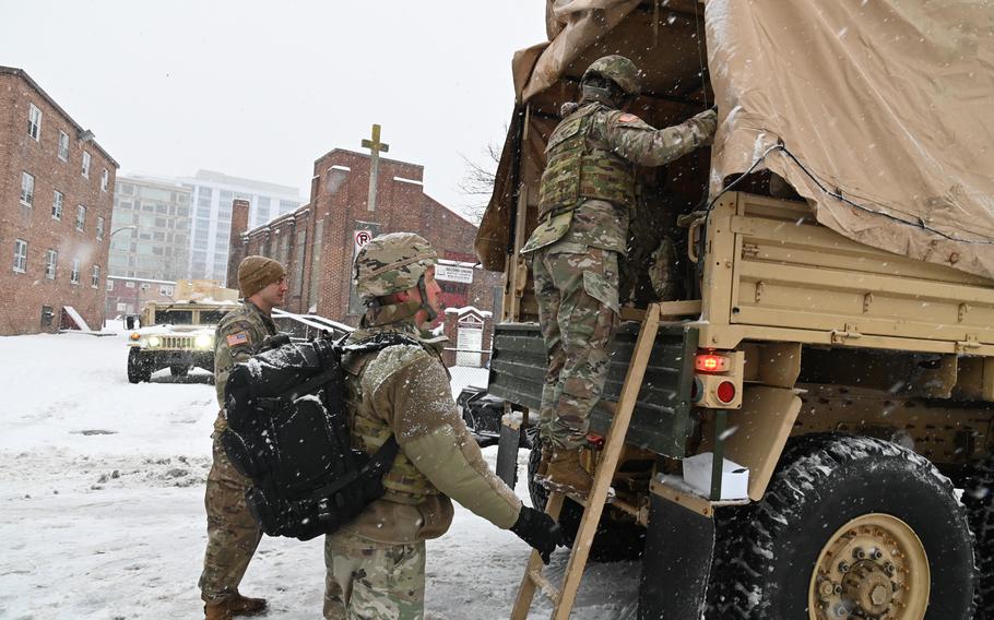 National Guard soldiers climb the back of a HMMWV