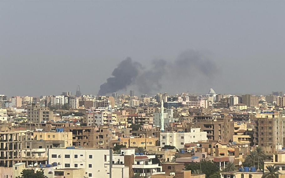 A plume of smoke rises over a city skyline.