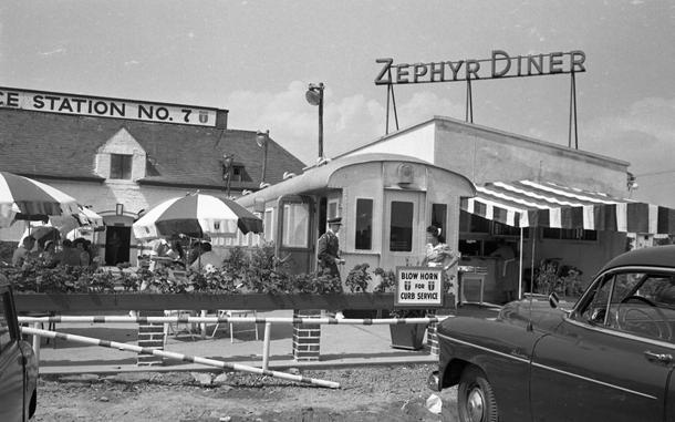 Roedelheim, Germany, June 17, 1950: Cheerful parasols are lined up on the outside terrace of the Zephyr Diner. A sign reading "Blow Horn For Curb Service" alerts patrons for the dine-in-your-car option.

The diner - which opened in 1949 as part of the European Exchange System - was located on the autobahn north of Frankfurt, on the Westerbachstrasse, Roedelheim. It was the first diner in the European Command area. It no longer exists, but it is unknown when it closed.

Stars and Stripes republished several of the images of the Zephyr diner over the years. All images taken by a Stars and Stripes photographer during one "assignment" are digitized by Stars and Stripes archives' staff. For the Zephyr diner assignment that meant a total of 45 images taken on both 35mm and 4x5 film. 

Check out additional images of the diner here and here. 

https://www.stripes.com/history/archive_photo_of_the_day/2022-07-25/zephyr-diner-germany-1950-6764113.html

https://www.stripes.com/history/archive_photo_of_the_day/2023-11-05/zephyr-diner-germany-1950-11882643.html

META TAGS: Europe; Germany; European Exchange Sytem; diner; dining; food service; leisure; military life; restaurant; fast food; Archives Month; preservation; 