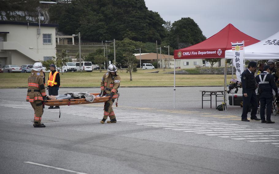 Japanese firefighters carry a man on a stretcher to a tent.