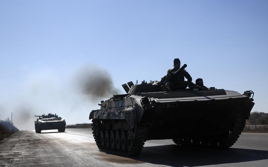 Syrian opposition fighters drive a seized seized Syrian army armored vehicle.