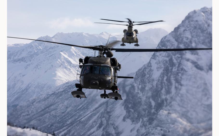 An Alaska Army National Guard UH-60L Black Hawk helicopter, foreground, and a CH-47F Chinook helicopter, fly between the Chugach Mountains during sling-load training near Joint Base Elmendorf-Richardson, Alaska, Feb. 28, 2024. 