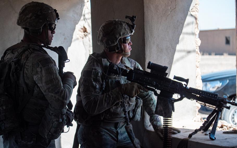 Two soldiers hold weapons during a patrol in northeast Syria.