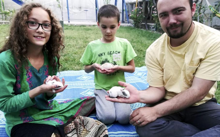 Ryan Corbett and children Miram and Caleb each hold a tiny rabbit.