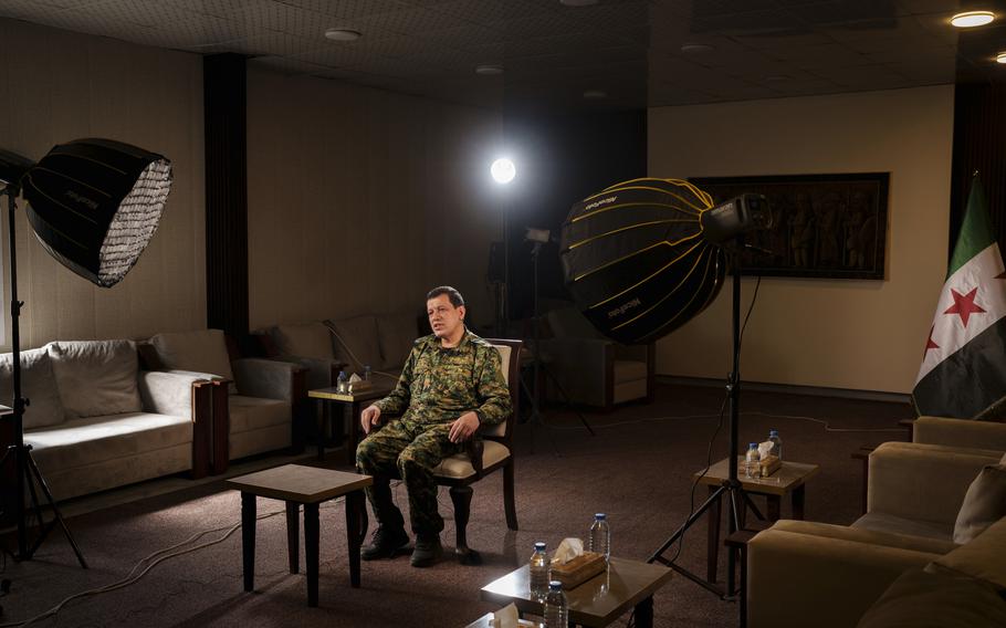 The commander sits under lights during an interview session.