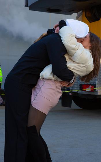 A sailor embraces and kisses a loved one.