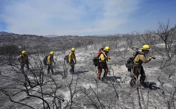 Members of Riverside County Cal Fire walk up a hillside while battling the Airport Fire Wednesday, Sept. 11, 2024, in El Cariso Village, in unincorporated Riverside, County, Calif. 