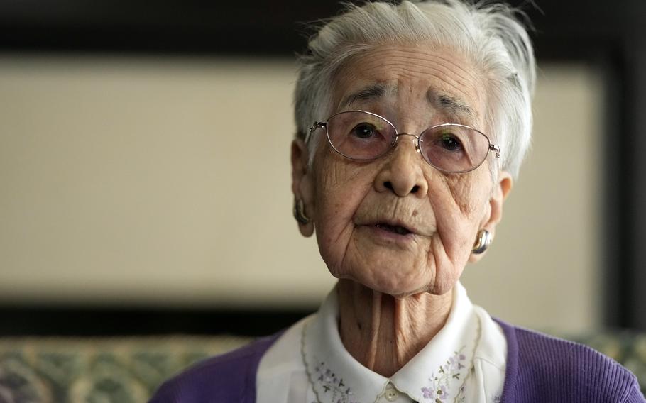 An elderly woman sits and speaks for an interview.