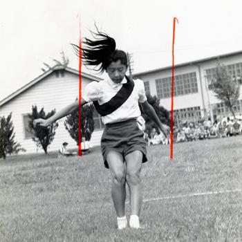 Keeping her balance, Michiko Myers lands after her effort in the running broad jump. Myers participated in the Junior Olympics, part of the Narimasu Elementary School, Grant Heights’ physical fitness program. Sixth graders who had just finished studying in Greece — the nation where the Olympic Games originated — staged an Olympics of their own.