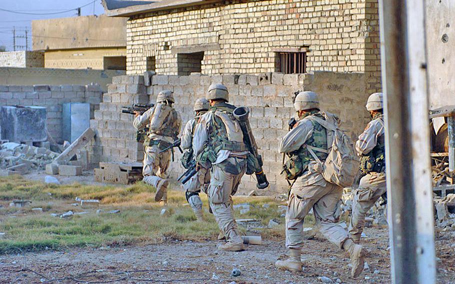 Five soldiers run with weapons as they clear houses in Fallujah, Iraq.