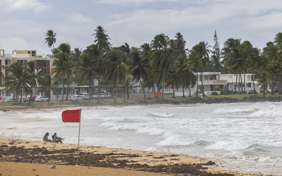 Tourists sit on La Pared beach as Tropical Storm Ernesto passes by Luquillo, Puerto Rico, on Aug. 13, 2024.