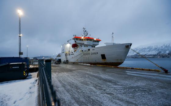 A white ship seen towed to a port on a cloudy and snowy day.