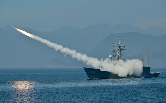 Smoke shrouds a naval vessel as it fires a missile from open water.