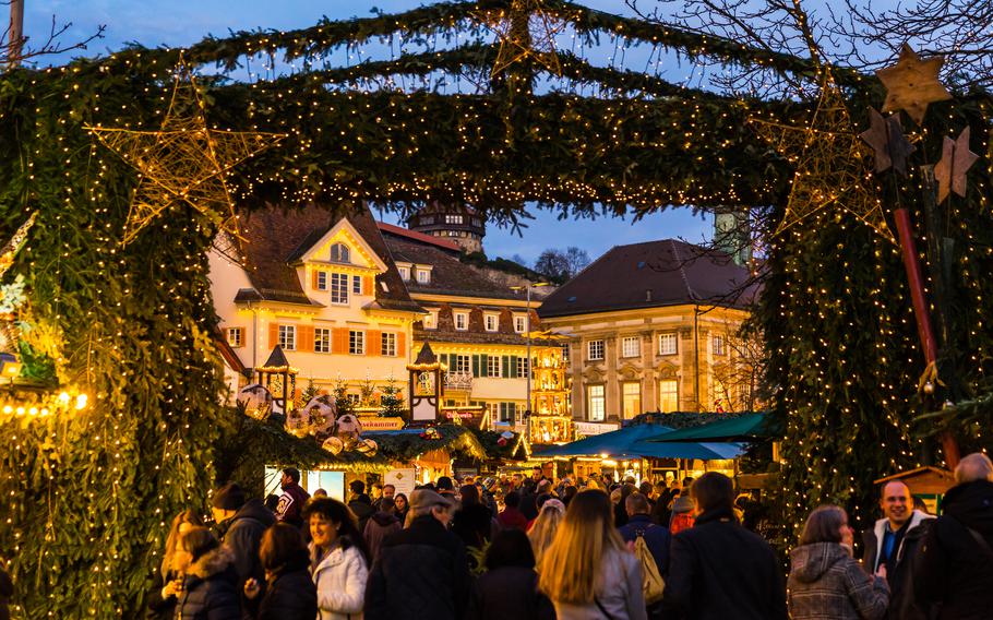 Tree boughs frame a view of buildings and people at the Christmas market in Esslingen, Germany.