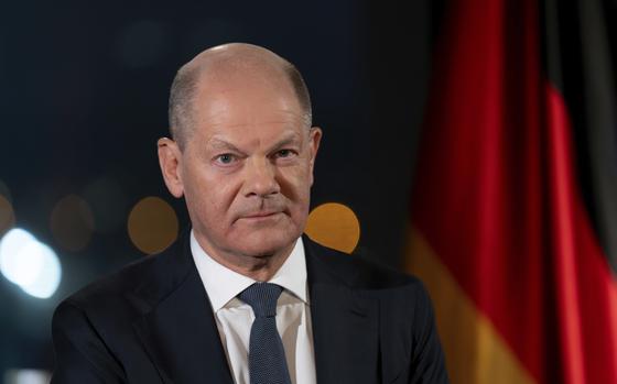 German Chancellor Olaf Scholz sits in front of the backdrop of the Reichstag illuminated by spotlights during a photo session after the recording of his New Year's address in the Chancellery in Berlin, Germany, Dec. 29, 2024. (Soeren Stache/dpa via AP)