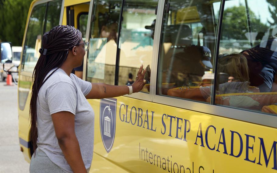 A parent saves to a child taking a bus to Global Step Academy, an international school popular with the community at Yokota Air Base, Japan, July 20, 2023.