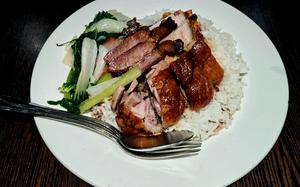 The duck and pork belly with barbecue pork fried rice at Charlie Chan in Cambridge, England. Leeks and onions are served alongside roast duck slices and pork belly. 

