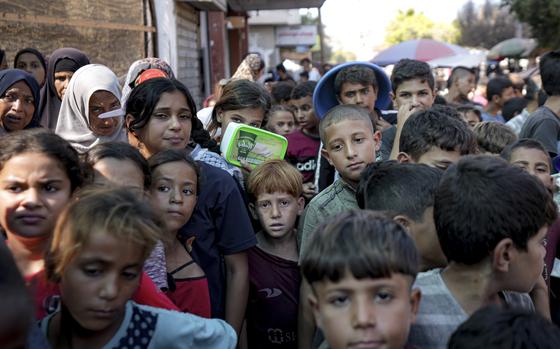 Displaced Palestinians in Gaza gather to receive distributed aid.