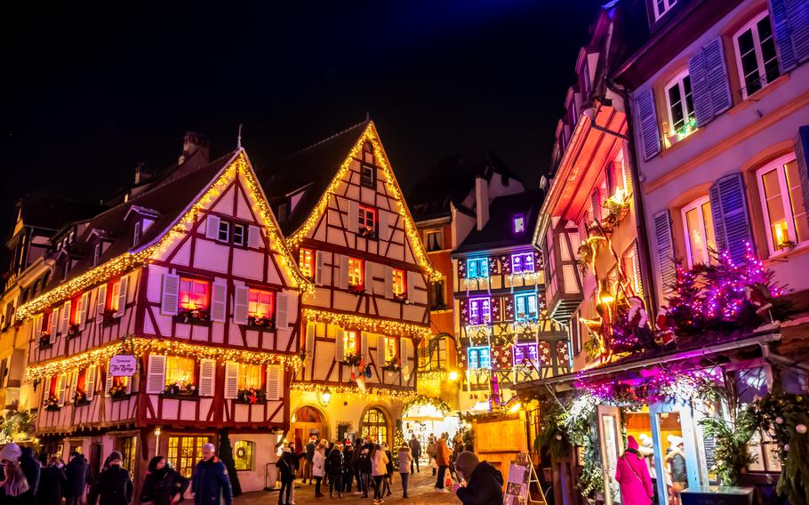 Half-timbered houses are festively lit at a city center market.