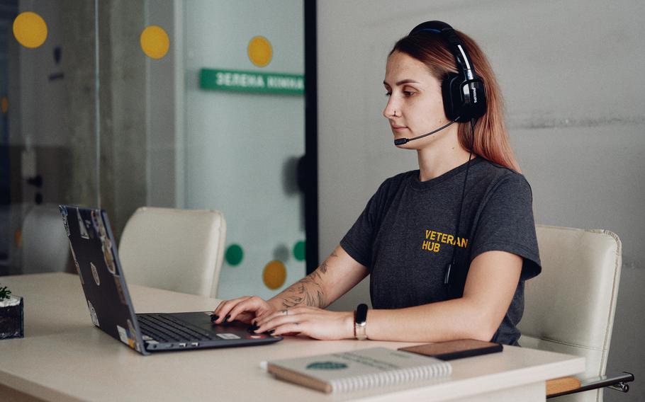 A woman looking at a computer answers a phone call.