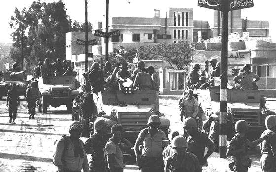 A black and white photograph shows Israeli troops entering Gaza City in the Gaza Strip.