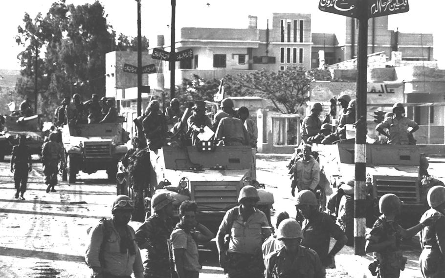 A black and white photograph shows Israeli troops entering Gaza City in the Gaza Strip.