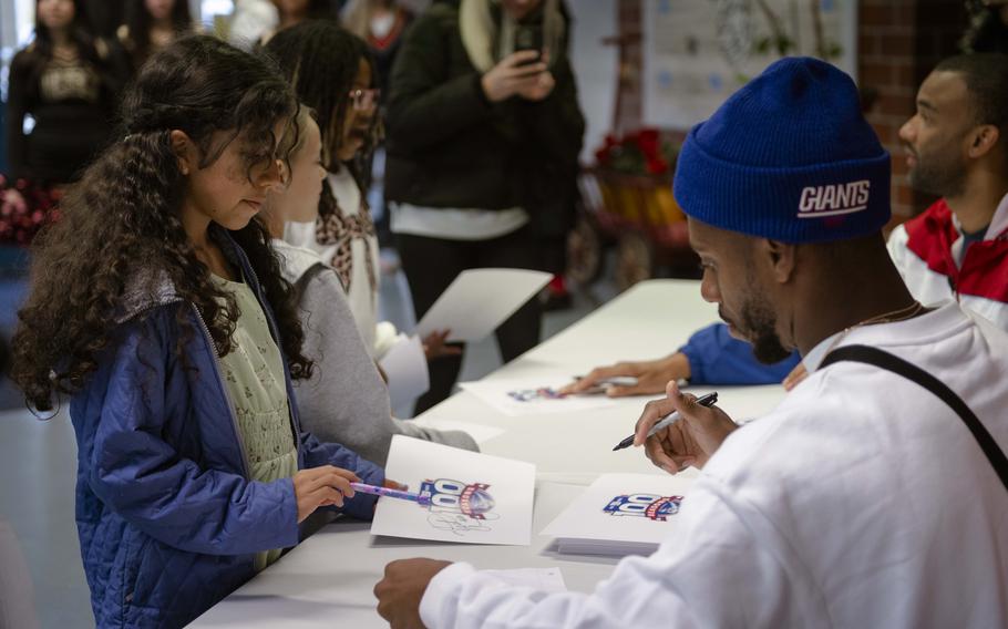 Former New York Giants wide receiver Victor Cruz signs a poster for a Vilseck Elementary School student during a visit Thursday. Cruz and fellow former Giants player Brandon London met with students on the U.S. Army post prior to the Giants’ game against the Carolina Panthers on Sunday. 