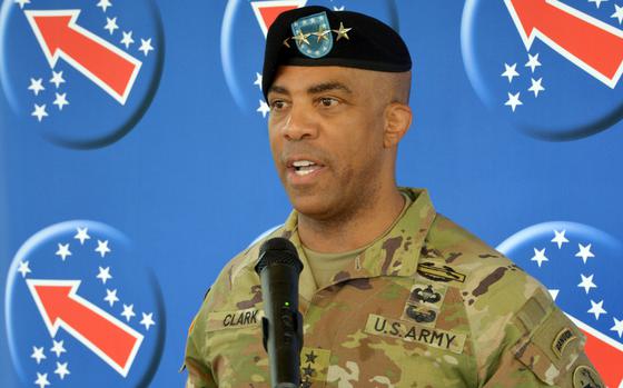 An Army officer in camoflauge uniform and black beret speaks into a microphone.