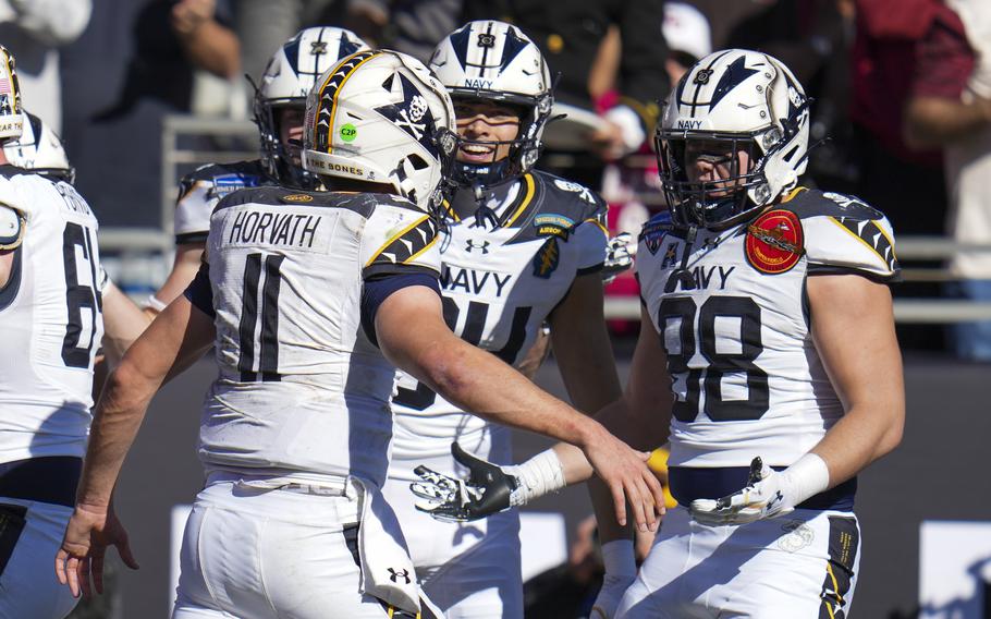 Navy quarterback Blake Horvath raises his arms to embrace teammates to celebrate a touchdown during a college football game.