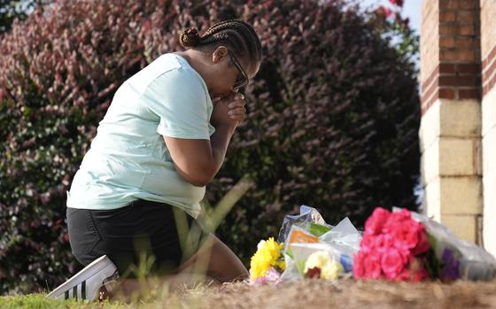 Linda Carter, of Grayson, Ga., kneels near Apalachee High School to place flowers as she mourns for slain students and teachers on Sept. 5, 2024, in Winder, Ga.