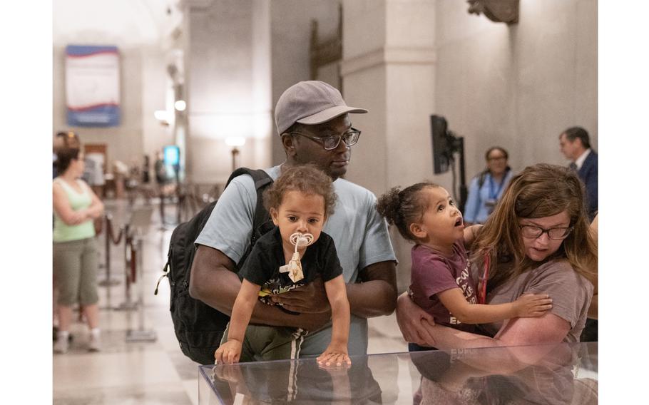 Jonathan Massaquoi, left, holds 1-year-old Miles while Colleen Massaquoi, far right, holds 3-year-old Zora as they view the Emancipation Proclamation at the National Archives in Washington on June 17, 2023.