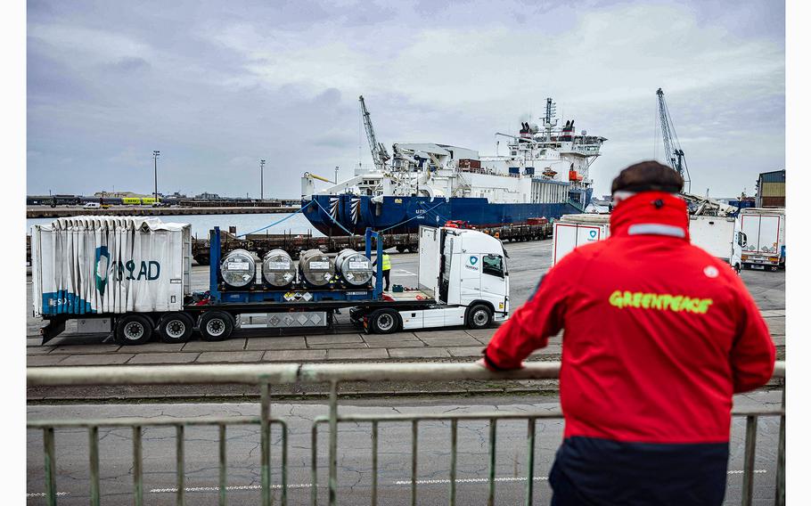 A Greenpeace activist observes the unloading of several cylinders of uranium from Russia at the port of Dunkirk, France, on March 20, 2023. 