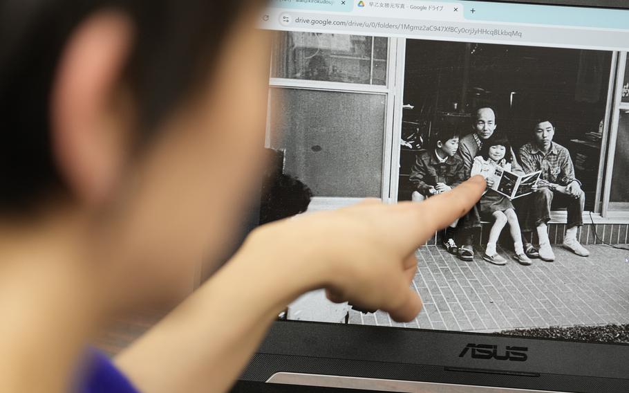 A woman points to a newly digitized black and white photo of her father with his family.