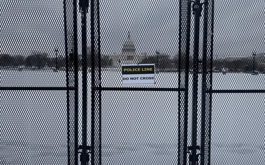 A fence, bearing a sign that says, “Police Line Do Not Cross,” around the Capitol. Snow covers the ground.