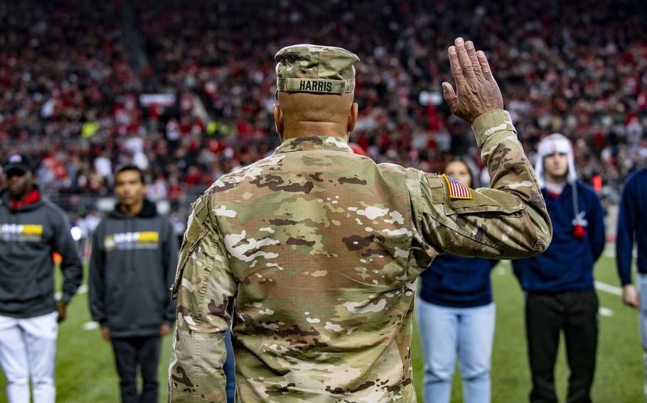 A view from behind as a military officer raises his right hand to administer the oath of enlistment to recruits.