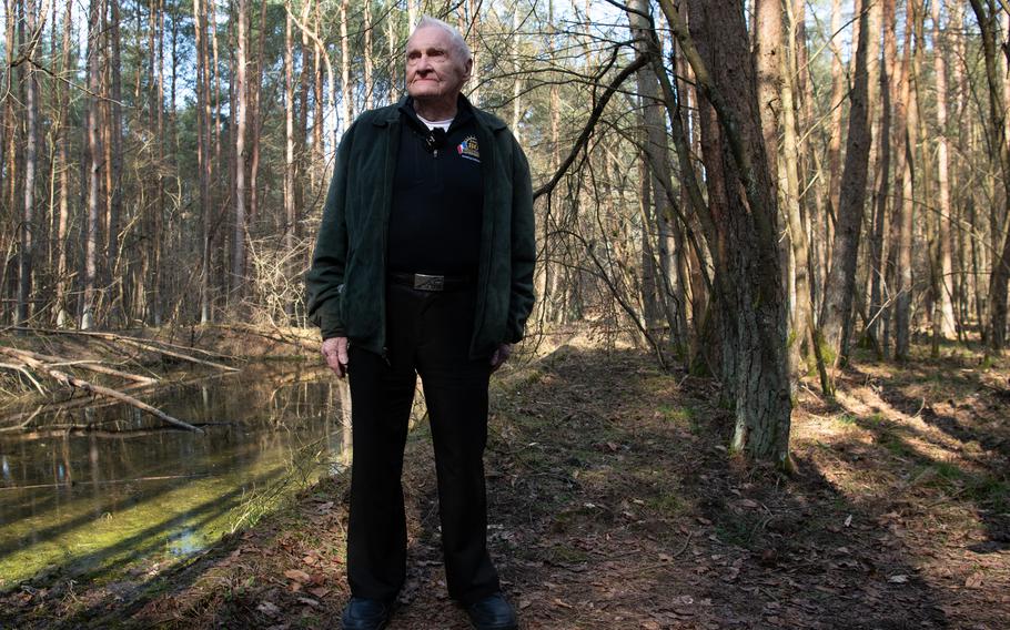 Lester Schrenk stands in the Poland forest, bare trees in the background.