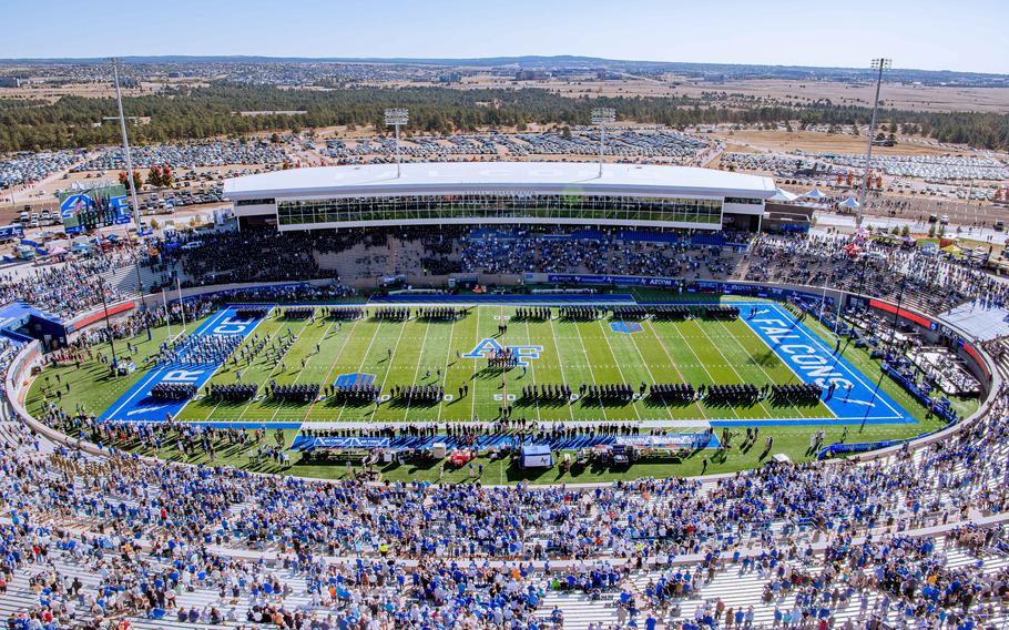 A crowd surrounds a large football field.