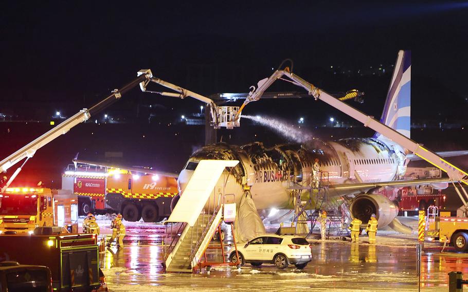 Firefighters work to extinguish a fire on an Air Busan airplane.