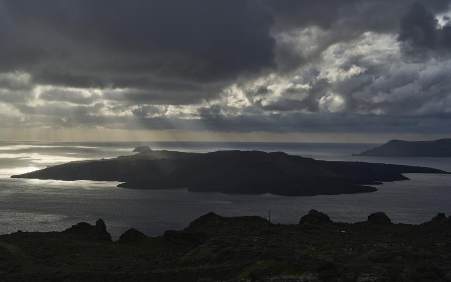 Sun rays illuminate the volcanic islet of Nea Kamen