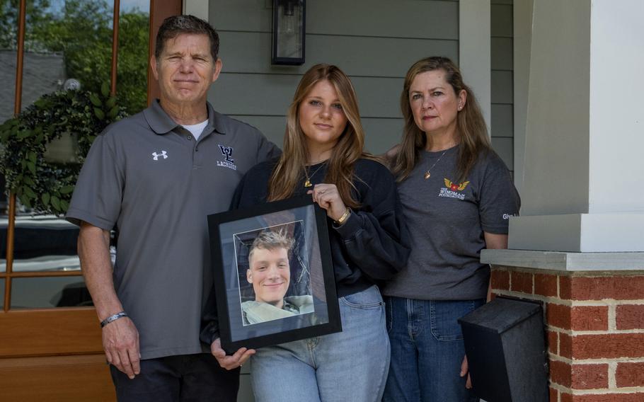 Family members of Spencer R. Collart, from left, father Bart Collart, sister Gwyneth Collart and mother Alexia Collart, hold his portrait as they pose for a photo at their home in Arlington, Va., on June 19, 2024.