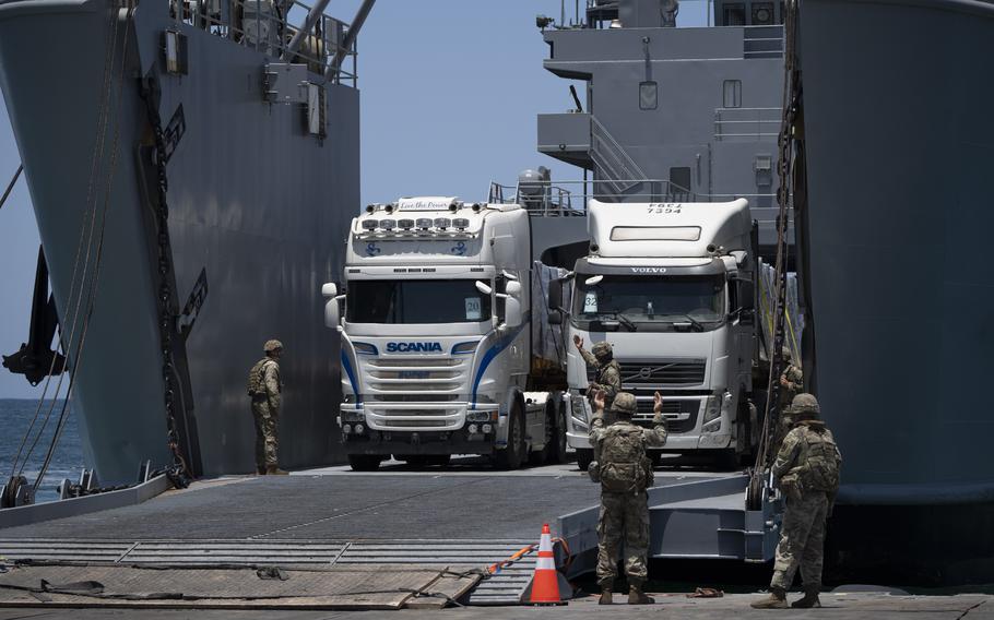 U.S. Army soldiers gestures as trucks loaded with humanitarian aid arrive at the U.S.-built floating pier Trident before reaching the beach on the coast of the Gaza Strip, Tuesday, June 25, 2024. 