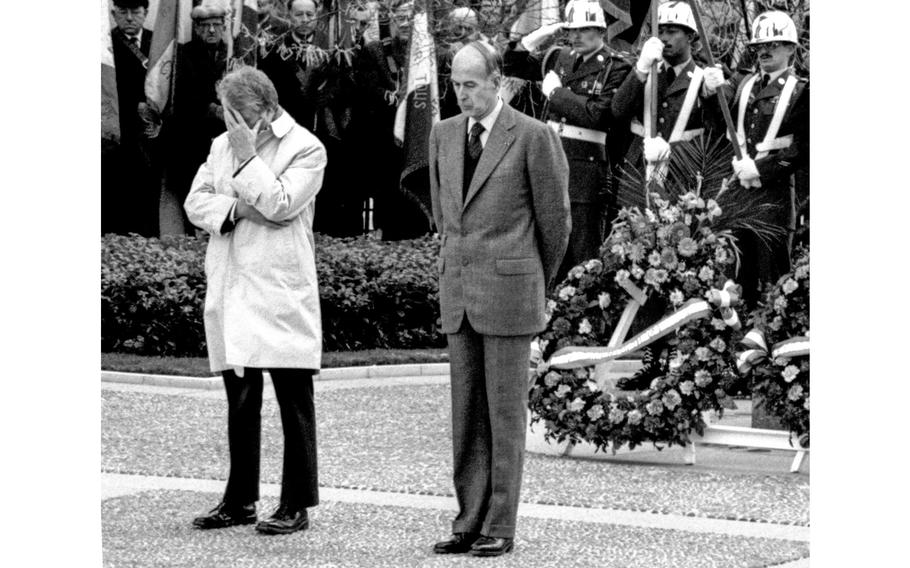 Jimmy Carter and the president of France bow their heads in reverance.