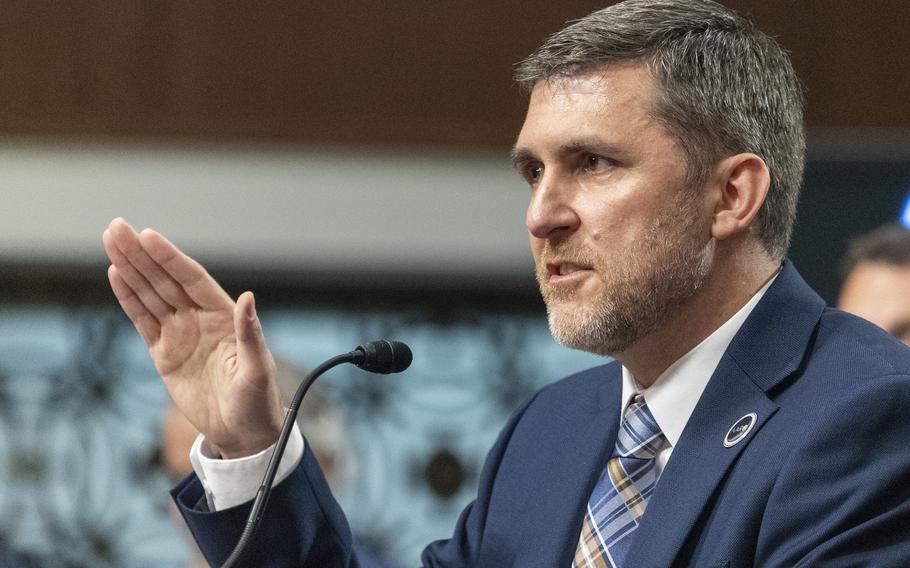 A man wearing a suit speaks into a microphone.