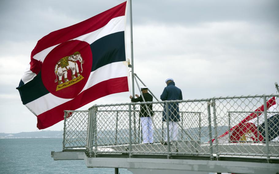 Thai sailors adjust their navy’s flag.