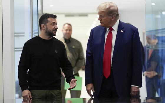 Volodymyr Zelenskyy talks to Donald Trump as the two walk down a hall.