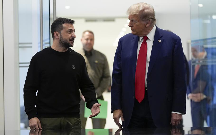 Volodymyr Zelenskyy talks to Donald Trump as the two walk down a hall.