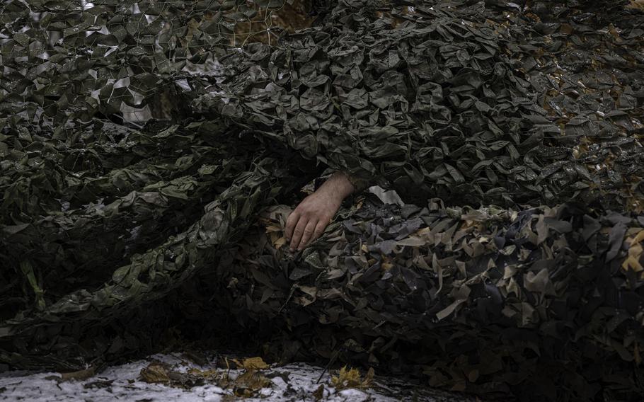 A hand emerges from a camouflage net.