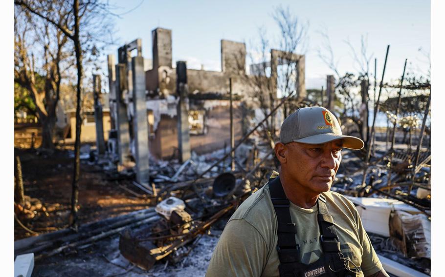 Archie Kalepa sits in his backyard that abuts a home that was destroyed in the fire on Monday, Aug. 14, 2023.